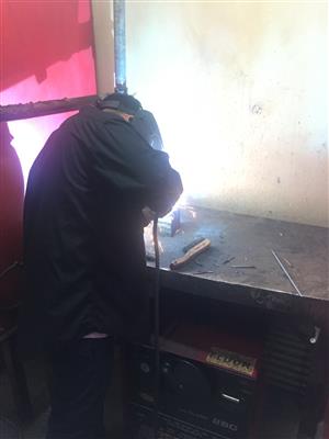Welding student wearing proper welding attire doing a weld Welding student wearing proper welding attire doing a weld
